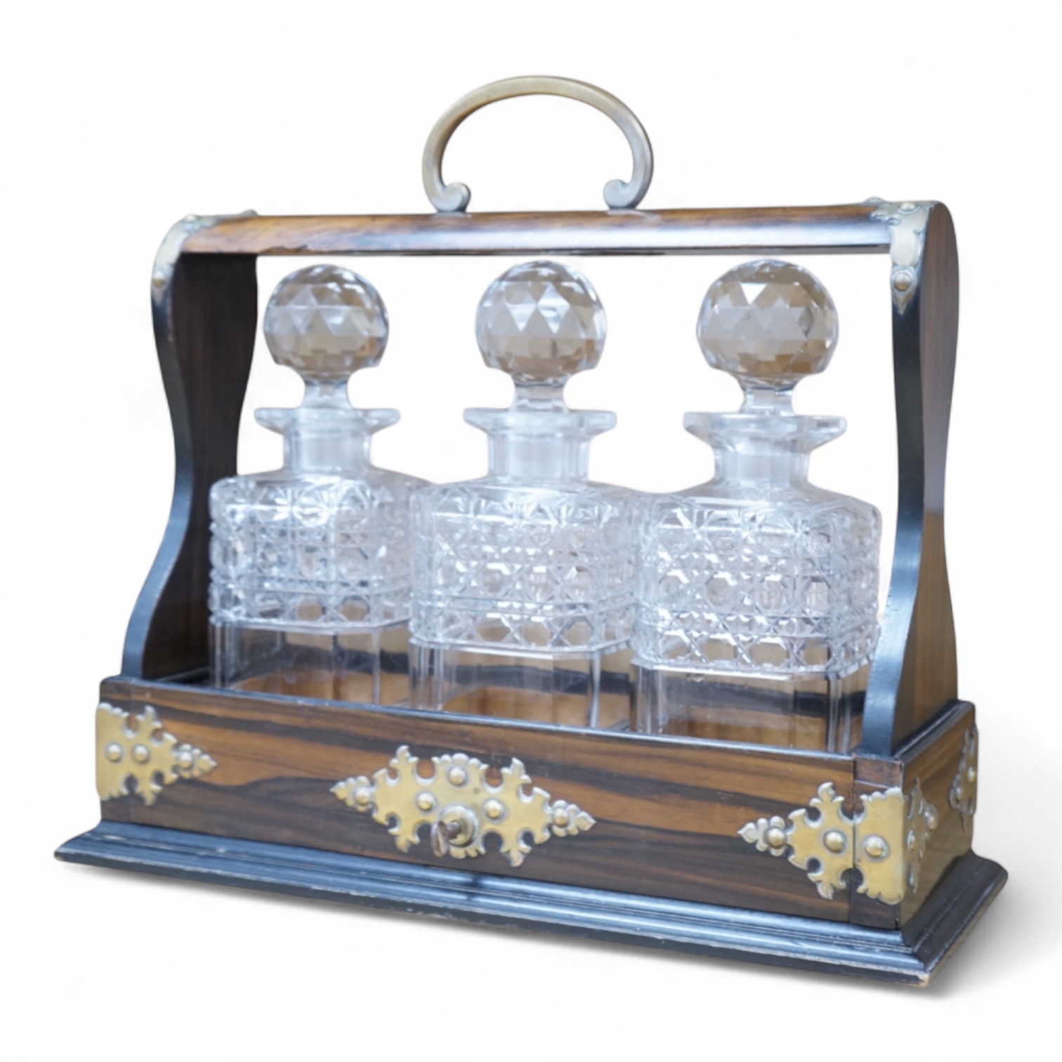 A Victorian coromandel three-bottle tantalus with brass mounts and original key